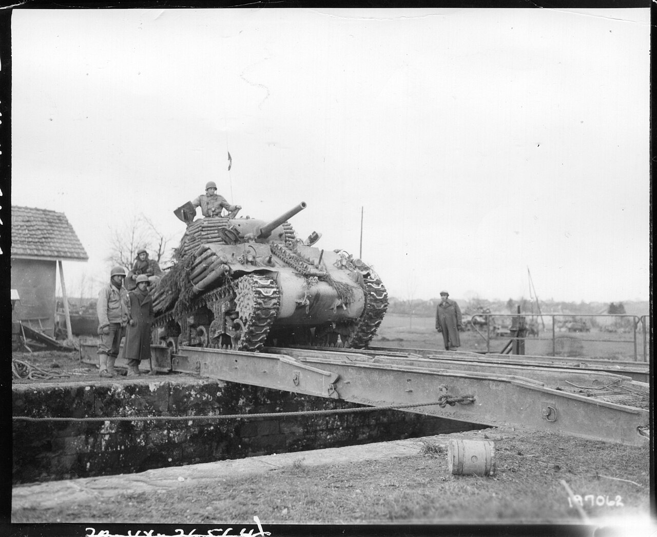 A Second World War tank crossing a temporary engineer bridge over a river