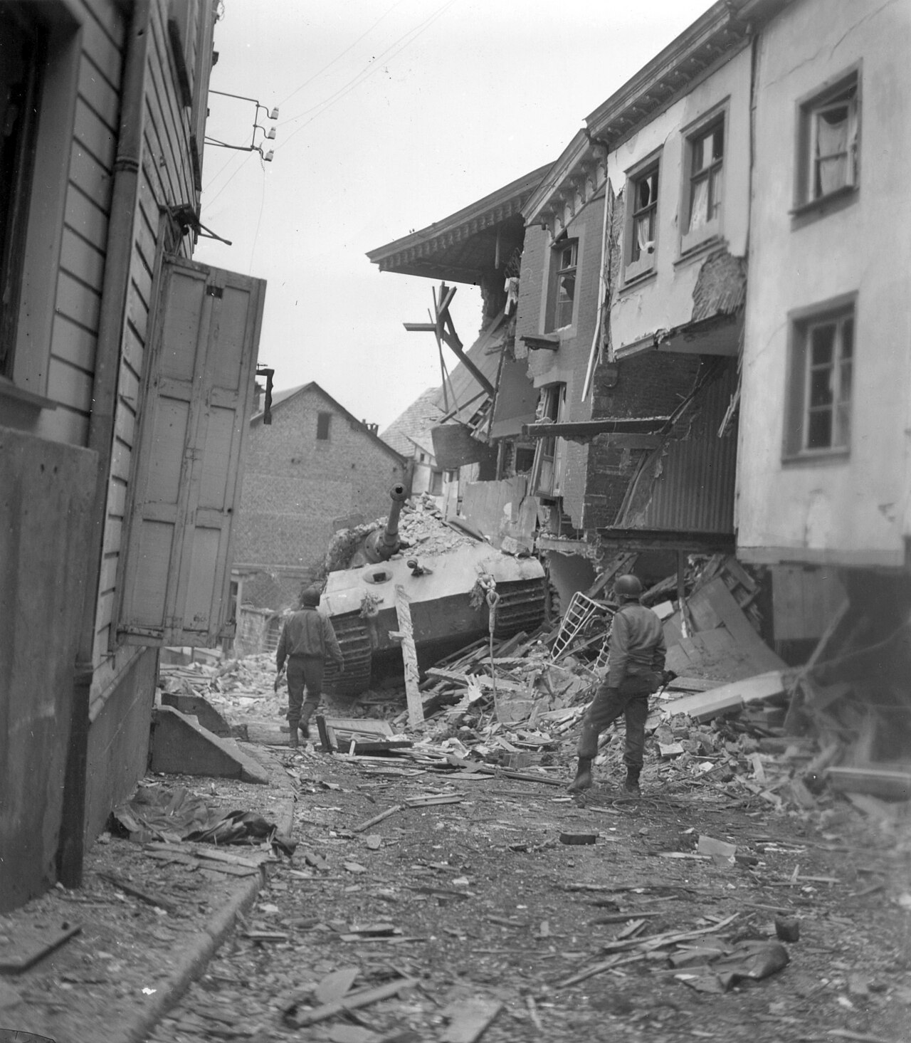 A heavy Second World War tank with thick frontal armour halted in a village street